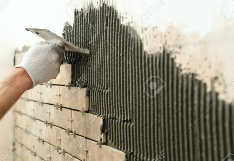 Trét keo dán gạch lên bề mặt tường cũ